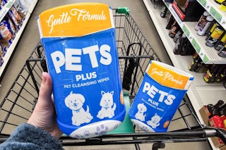 person holding a package of pet cleansing wipes over a cart