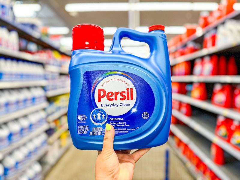 hand holding a bottle of persil liquid detergent in walmart aisle