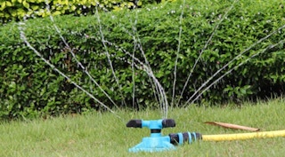 a blue sprinkler squirting water on a lawn
