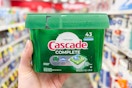 person holding a tub of cascade dishwasher pods in an aisle
