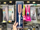 a hand holding a box with a Conair hair waver on it in a store aisle 