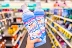 person holding 2 suavitel fabric softeners in an aisle