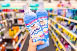 person holding 2 suavitel fabric softeners in an aisle