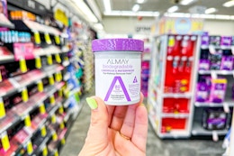 person holding almay makeup remover pads in an aisle