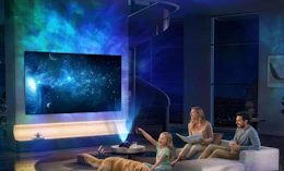 a galaxy light projecting on a wall and TV in room with a family