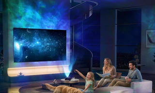 a galaxy light projecting on a wall and TV in room with a family