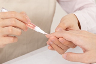 a person applying cuticle oil to someone's nails