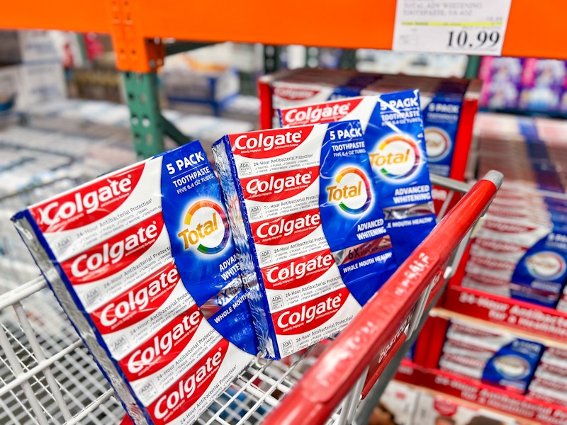 a three pack of colgate toothpaste in a costco cart