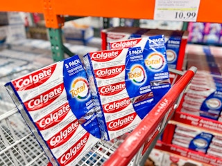 a three pack of colgate toothpaste in a costco cart