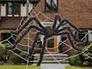 a giant faux spider in a web in front of a house