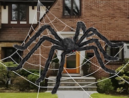 a giant faux spider in a web in front of a house