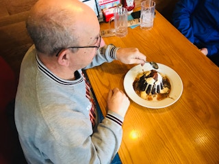 A senior sitting at a booth in Chili's, about to start eating a dessert.