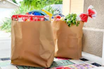 two brown paper bags filled with groceries and school supplies on a doorstep delivered by instacart