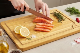 a woman using a wooden cutting board