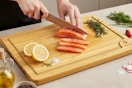 a woman using a wooden cutting board