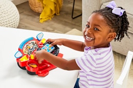 Lifestyle image of child playing with the Vtech Paw Patrol Rescue Driver ATV & Fire Truck Toy