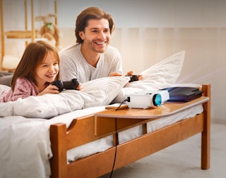 a dad and daughter playing video games with a projector