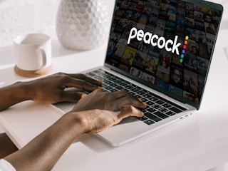 A person using a laptop with the Peacock starting screen displayed.