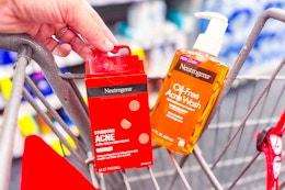 person placing neutrogena acne patches in a cart with face wash in it
