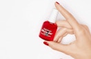 a hand holding a red bottle of nail polish