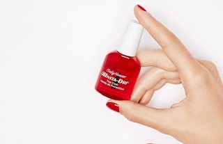 a hand holding a red bottle of nail polish