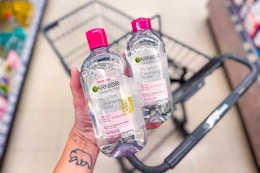 person holding 2 bottles of garnier micellar water over a cart