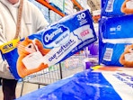 woman grabbing a pack of Charmin toilet paper and adding it to a shopping cart at Costco