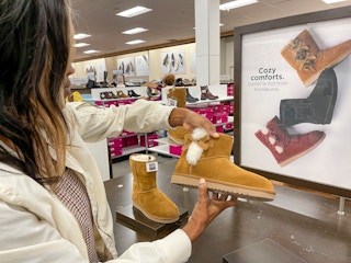 A woman looking at boots inside Kohls