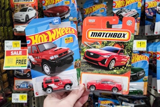 hand holding matchbox and hot wheels play cars at dollar general