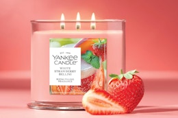 a pink candle with strawberries on a pink background