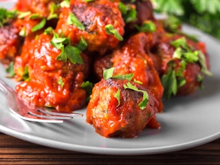 meatballs in marinara sauce and parsley on plate