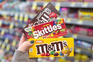 hand holding three m&M and skittles theatre box candy
