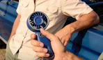 a person holding a blue portable fan