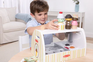 lifestyle image of a child playing with a melissa & doug ice cream playset