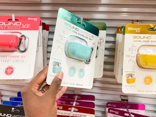 A person's hand taking a pair of Tzumi wireless earbuds from a display of them.