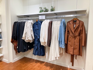 A variety of clothes hanging from store rack.