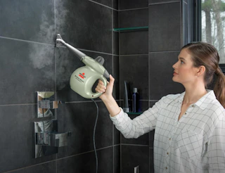 a person steam cleaning tile in a shower 
