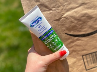 hand holding benadryl anti-itch gel cream and an amazon envelope