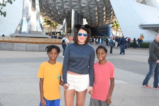 A mom and her two kids standing in front of Epcot's Spaceship Earth experience.