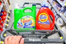 person pushing a cart with large tide and gain detergents in it