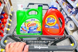 person pushing a cart with large tide and gain detergents in it