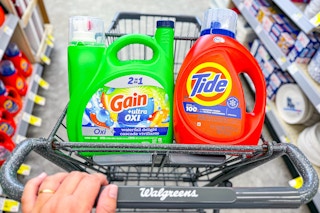 person pushing a cart with large tide and gain detergents in it