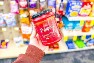 person holding a container of folgers coffee