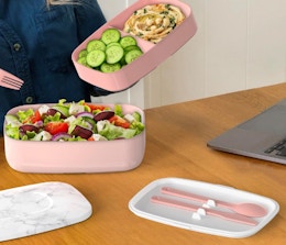 a person eating out of a pink bento box