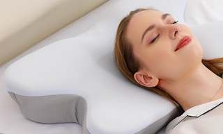 a woman laying on a cervical pillow
