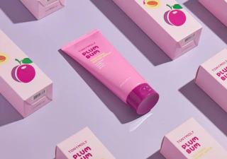 a pink tube of face serum on display with the packaging