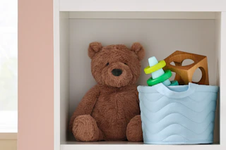 Cloud Island blue basket used to store toys next to a plush bear