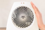 Lifestyle image of the Vornado Indoor Heater with hand placed on the side