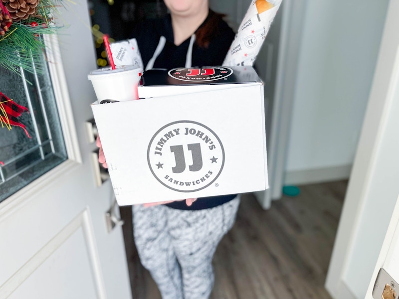 woman holding box of jimmy johns delivery