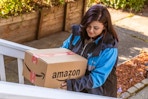 an amazon delivery driver walking up stair with a package